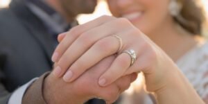 Casal de m ãos dadas com an el, sorrindo gentilmente.